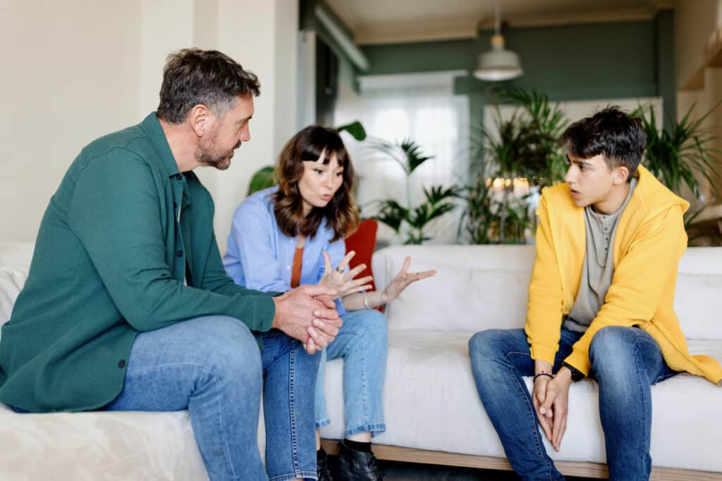 Family discussing with their teenage son at home struggling with toxic family dynamic due to addiction