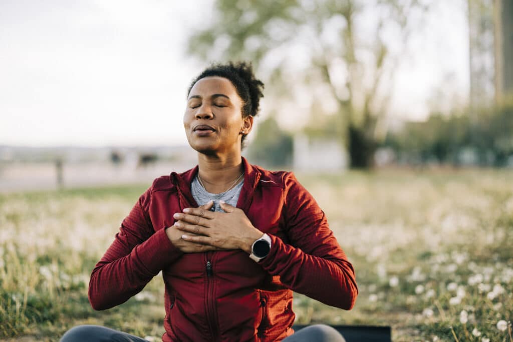 Black woman, breath and hand on chest, for meditation and wellness to regulate emotions